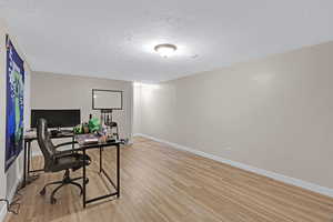 Office area with light wood-type flooring and a textured ceiling