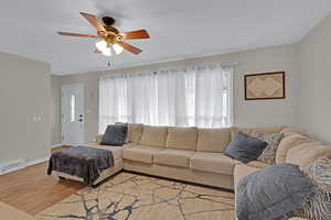 Living room with ceiling fan and light hardwood / wood-style floors