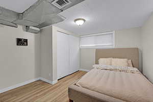 Bedroom with hardwood / wood-style flooring, a closet, and a textured ceiling