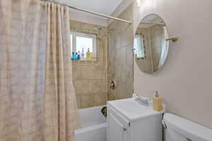 Full bathroom featuring toilet, vanity, and shower / bathtub combination with curtain