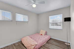 Bedroom featuring multiple windows, ceiling fan, and dark hardwood / wood-style floors