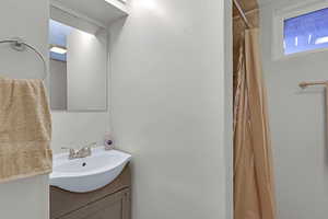 Bathroom with a shower with shower curtain and vanity