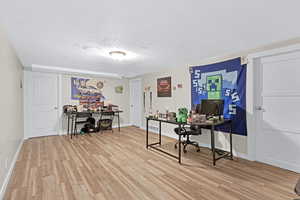 Office area with light hardwood / wood-style floors and a textured ceiling