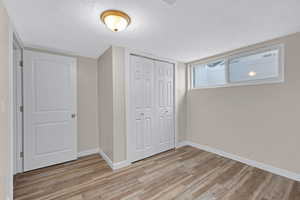 Unfurnished bedroom featuring light hardwood / wood-style floors, a closet, and a textured ceiling