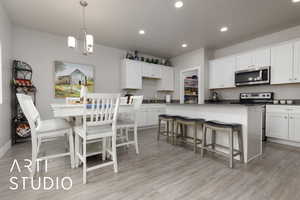 Kitchen featuring appliances with stainless steel finishes, white cabinetry, and a kitchen bar