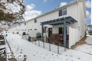 Snow covered rear of property featuring a pergola