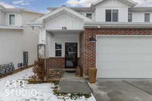 Snow covered property entrance with a 2-car garage