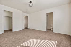 Unfurnished bedroom with carpet, a textured ceiling, and connected bathroom