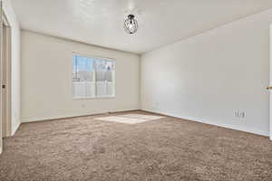 Empty room with carpet and a textured ceiling