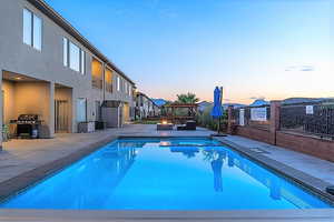 Pool at dusk featuring central AC, grilling area, a patio, and an outdoor fire pit