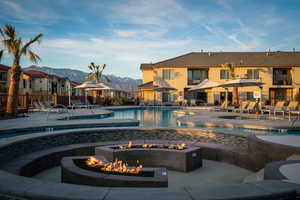 View of pool featuring a mountain view, a patio area, a hot tub, and an outdoor fire pit