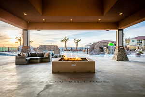 Patio terrace at dusk with an outdoor living space with a fire pit