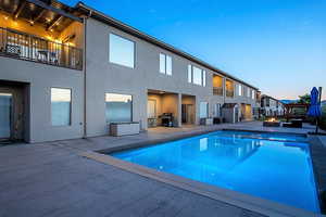 Pool at dusk featuring a patio, area for grilling, and an outdoor fire pit