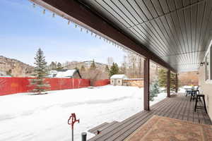 Snow covered deck featuring a mountain view and a storage unit