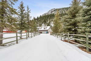 Driveway layered in snow featuring a garage and a mountain view