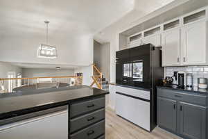 Kitchen featuring white cabinetry, gray cabinetry, hanging light fixtures, and dishwashing machine