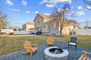 Back of house featuring an outdoor fire pit, a yard, and central AC