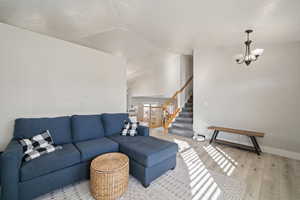 Living room featuring light wood-type flooring, a chandelier, and lofted ceiling