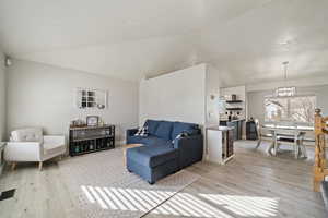 Living room with vaulted ceiling and light hardwood / wood-style flooring