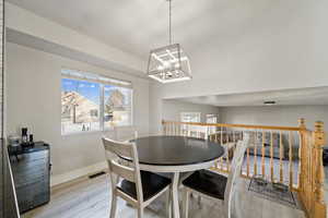 Dining area with light hardwood / wood-style floors and a chandelier