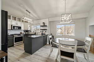 Kitchen with white cabinetry, decorative light fixtures, sink, tasteful backsplash, and stainless steel gas range oven