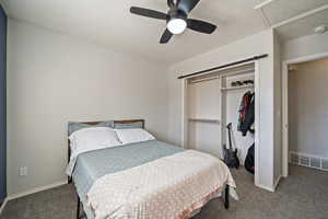 Bedroom featuring dark carpet, ceiling fan, and a closet