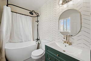 Full bathroom featuring toilet, separate shower and tub, and vanity