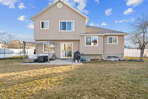 Rear view of property featuring a patio, a trampoline, and a lawn