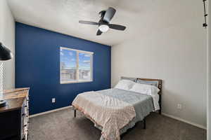 Carpeted bedroom featuring ceiling fan and a textured ceiling