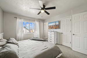 Bedroom featuring a textured ceiling, light carpet, and ceiling fan