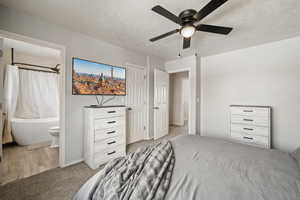 Bedroom featuring ceiling fan, light carpet, a textured ceiling, and connected bathroom