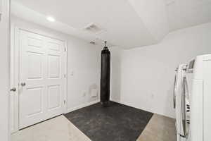 Exercise area with washing machine and dryer and vaulted ceiling