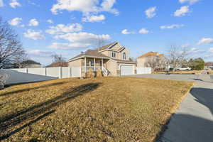 View of front of home with covered porch, a front yard, and a garage