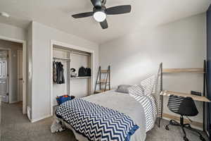 Carpeted bedroom featuring ceiling fan and a closet