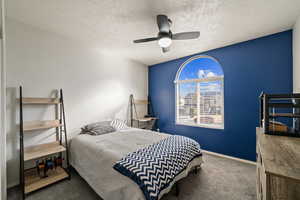 Bedroom featuring dark carpet, ceiling fan, and a textured ceiling