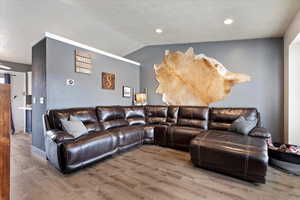 Living room with a textured ceiling, hardwood / wood-style flooring, and lofted ceiling