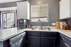 Kitchen featuring white cabinetry, sink, and black dishwasher