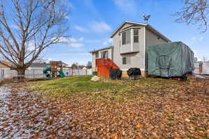 Rear view of house with a playground, a trampoline, and a lawn