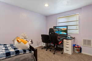 Carpeted home office with a textured ceiling