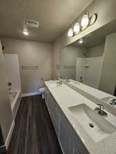 Full bathroom featuring hardwood / wood-style flooring, vanity, a textured ceiling, shower / bathtub combination, and toilet