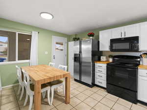 Kitchen featuring white cabinetry, black appliances, tasteful backsplash, and light tile patterned floors