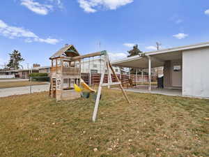 View of jungle gym with a patio and a lawn