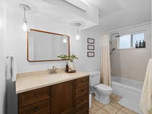 Full bathroom with toilet, tile patterned flooring, vanity, and shower / tub combo