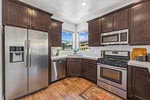 Kitchen featuring sink, dark brown cabinets, stainless steel appliances, and light hardwood / wood-style floors