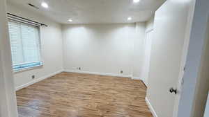 Unfurnished room with a textured ceiling and light hardwood / wood-style flooring