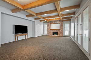 Unfurnished living room featuring french doors, coffered ceiling, beamed ceiling, carpet, and a brick fireplace