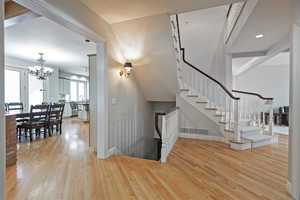 Stairway featuring wood-type flooring and a notable chandelier