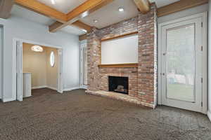 Unfurnished living room featuring dark carpet, coffered ceiling, a fireplace, and beam ceiling