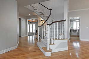 Stairs with hardwood / wood-style flooring, ornamental molding, and a towering ceiling