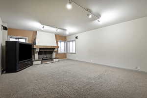 Unfurnished living room featuring track lighting and carpet floors